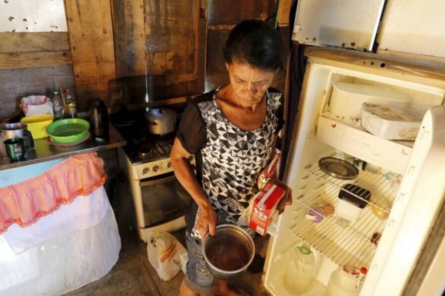 Mulher mostra panela e geladeira vazias