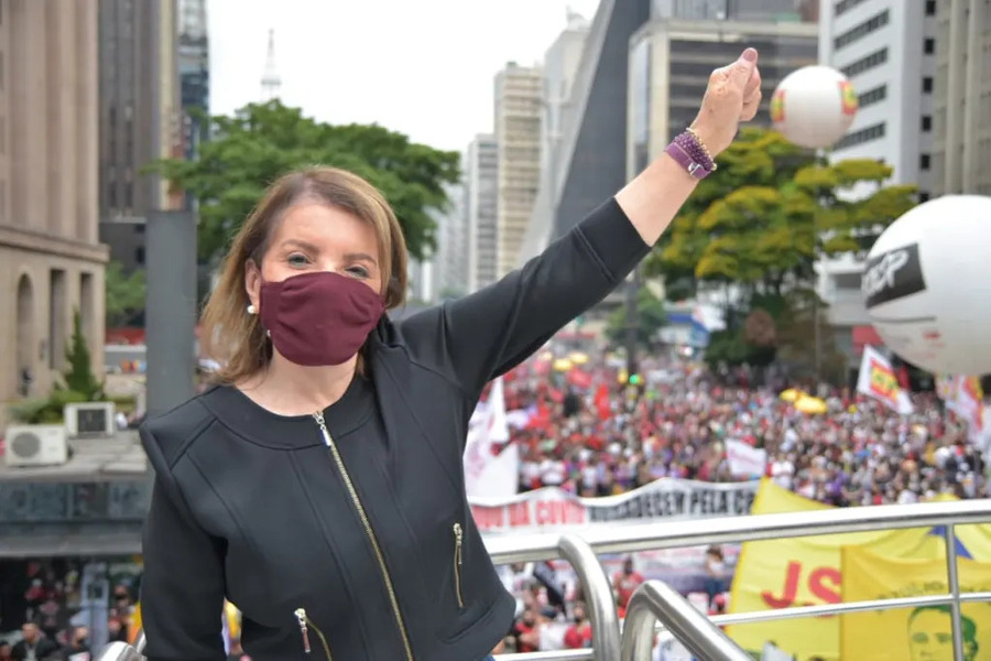 Deputada Estadual Professora Bebel no caminhão de som está de frente para a câmera e com o braço esquerdo estendido