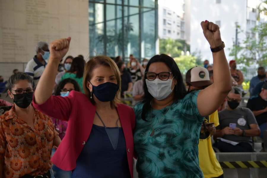 Deputada Estadual Professora Bebel, à esquerda, e a vereadora Juliana Cardoso, à direita. Ambas está de frente pra nós e com os braços levantados e punhos cerrados.