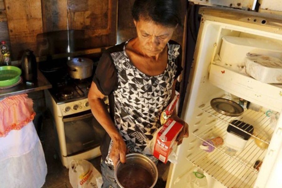 Mulher mostra panelas e geladeira vazias 