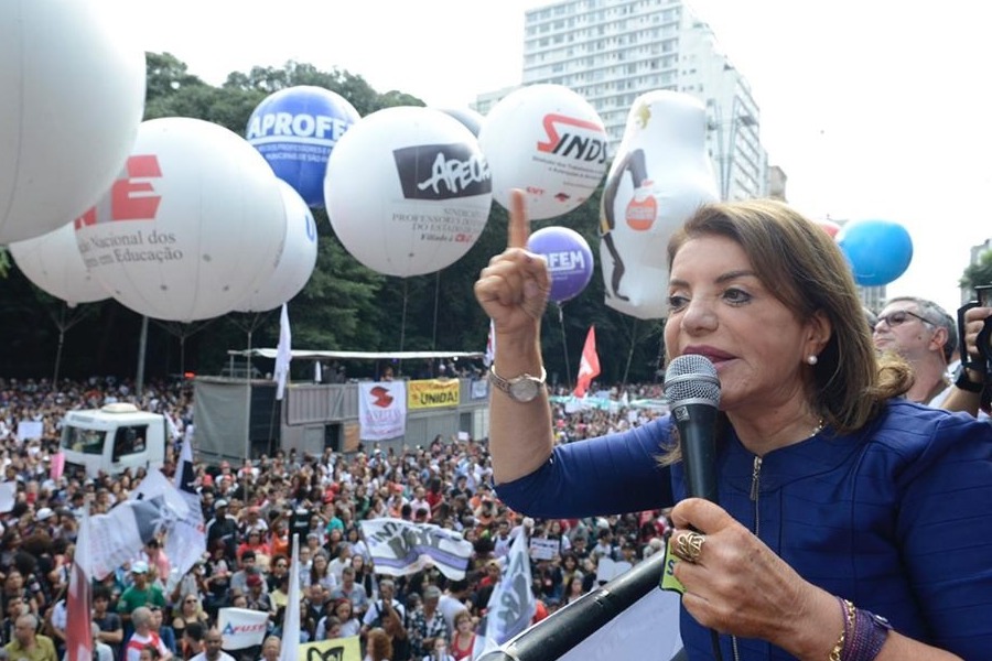 Foto da Deputada Estadual Professora Bebel falando ao microfone em ato público