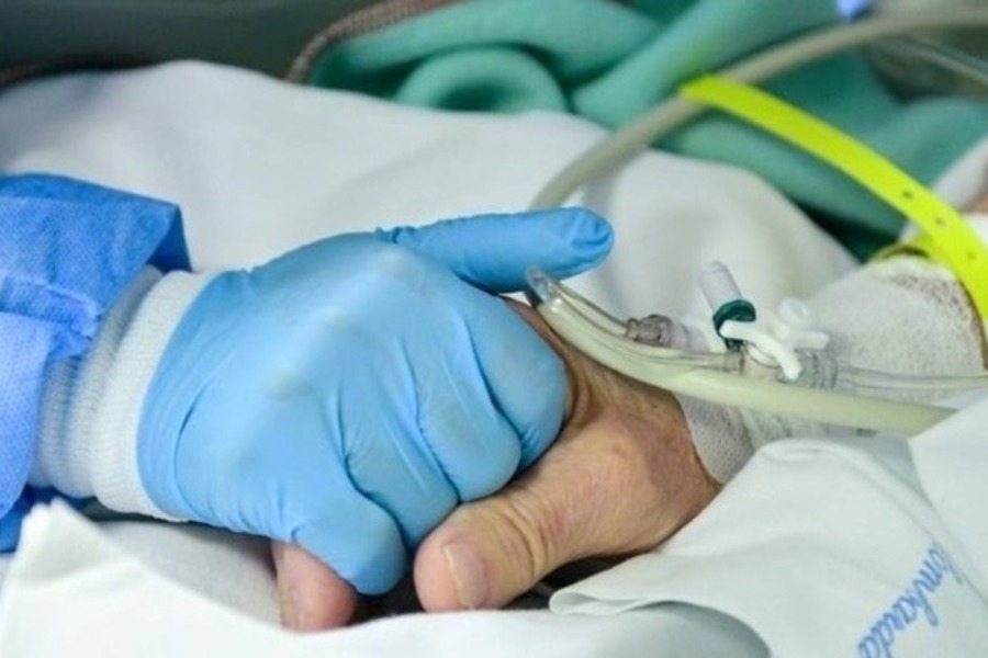 Mão de um enfermeiro segura a mão de um paciente no leito de hospital