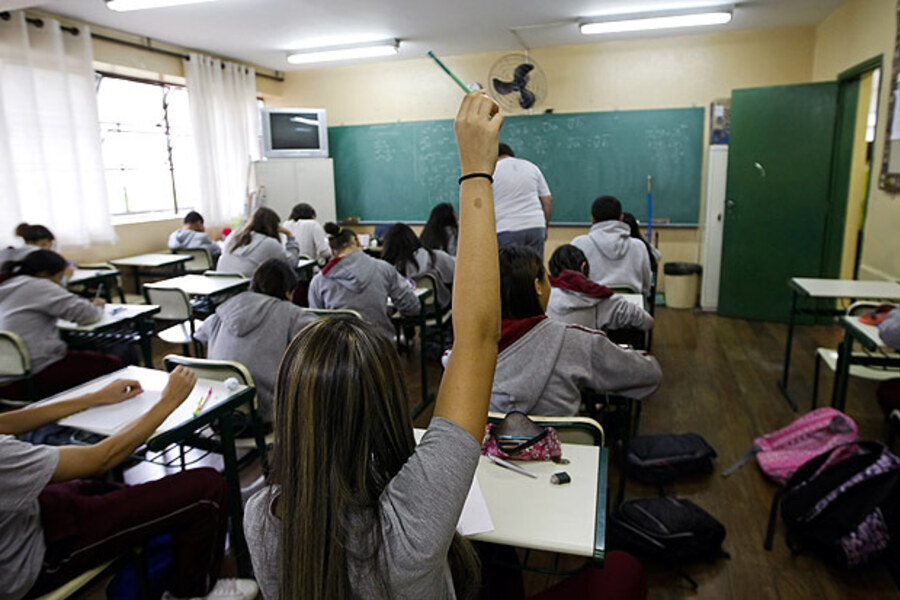 Aluna levanta a mão para fazer uma pergunta à professora em sala de aula