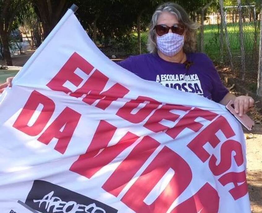 Professora mostra bandeira da Apeoesp escrito "Em defesa da Vida"