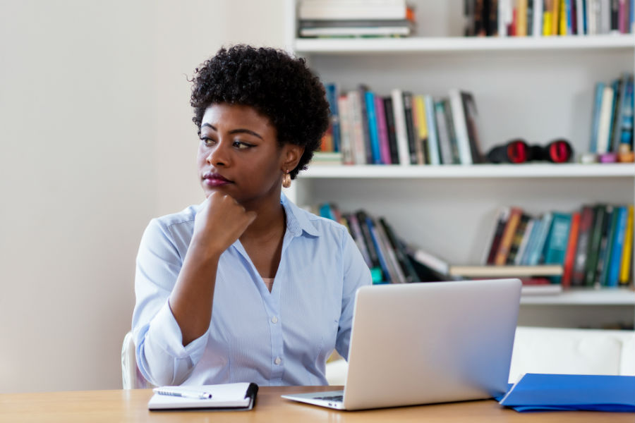 Mulher negra reflete em frente laptop em seu local de trabalho