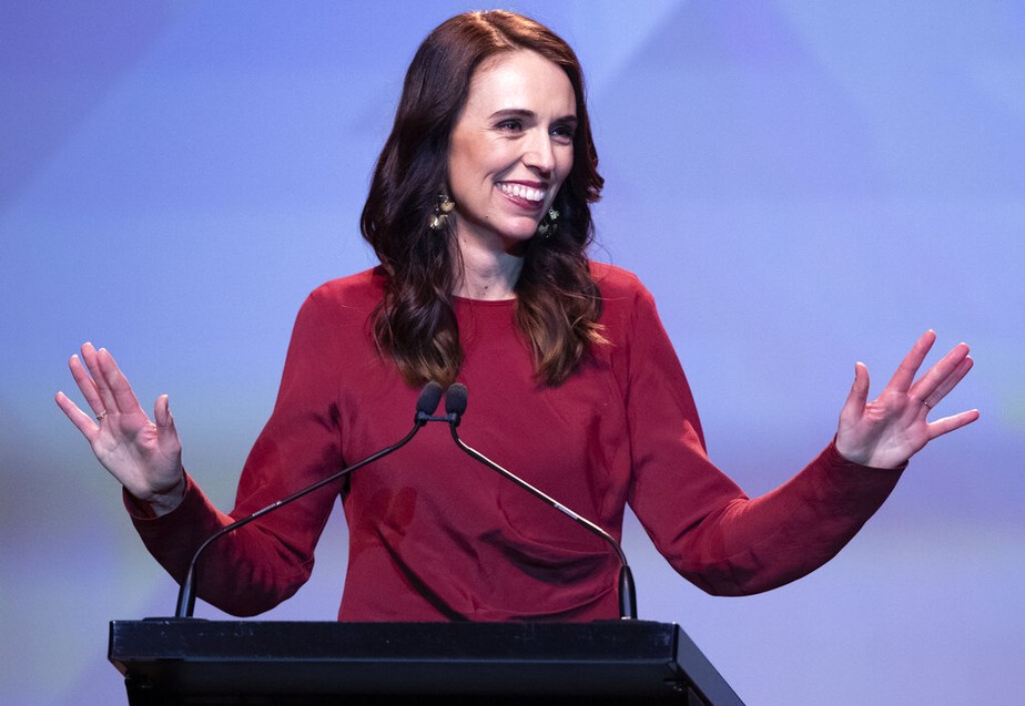 Foto de Jacinda no palco discursando de braços abertos depois da vitória