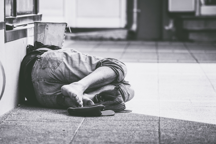 Foto de um adolescente em situação de rua dormindo na calçada