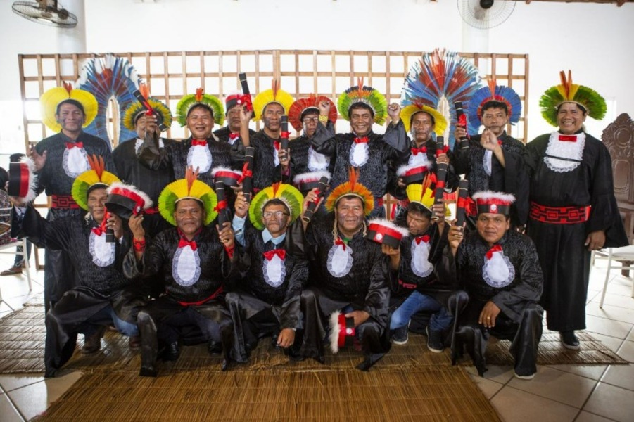 Foto de um grupo de indígenas, vestidos com toga e cocar, posam em dia de formatura