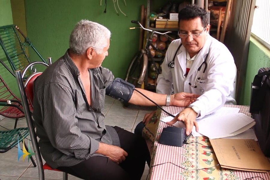 Médico visita paciente em sua casa. Está examinando sua pressão