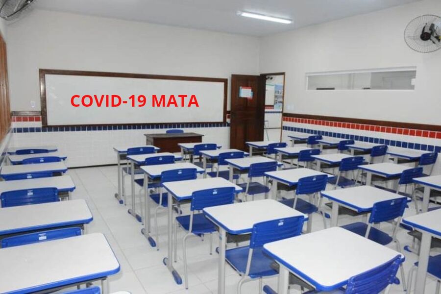 Foto de uma sala de aula vazia com a inscrição "Covid-19 Mata" escrito na lousa