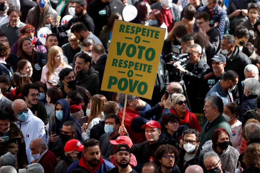 Pessoa ergue cartaz no meio da multidão em que se pode ler: respeito o voto, respeito o povo