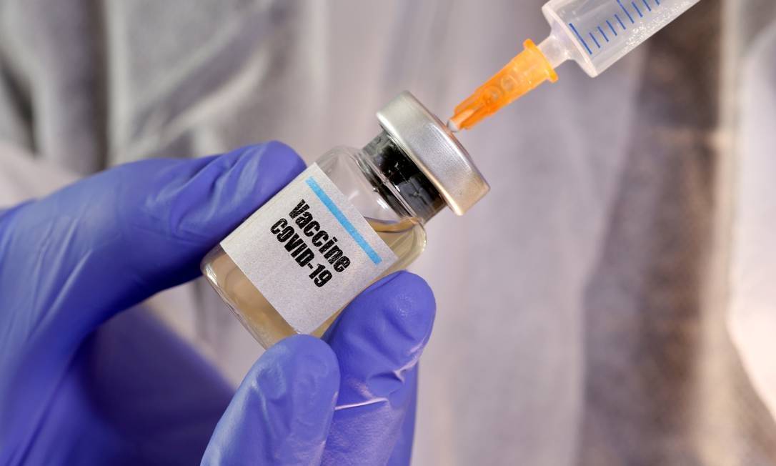 Foto de enfermeiro tirando vacina do frasco com a seringa